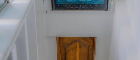 A wooden door at the bottom of a staircase with a framed picture above it.