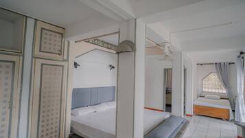 A bedroom with a bed, a wardrobe, and a window with curtains.
