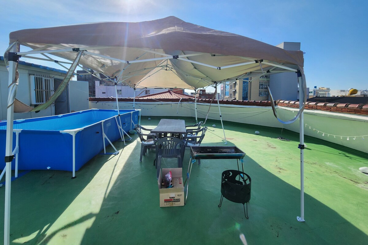 A rooftop terrace with a pool, a table, and a covered seating area.