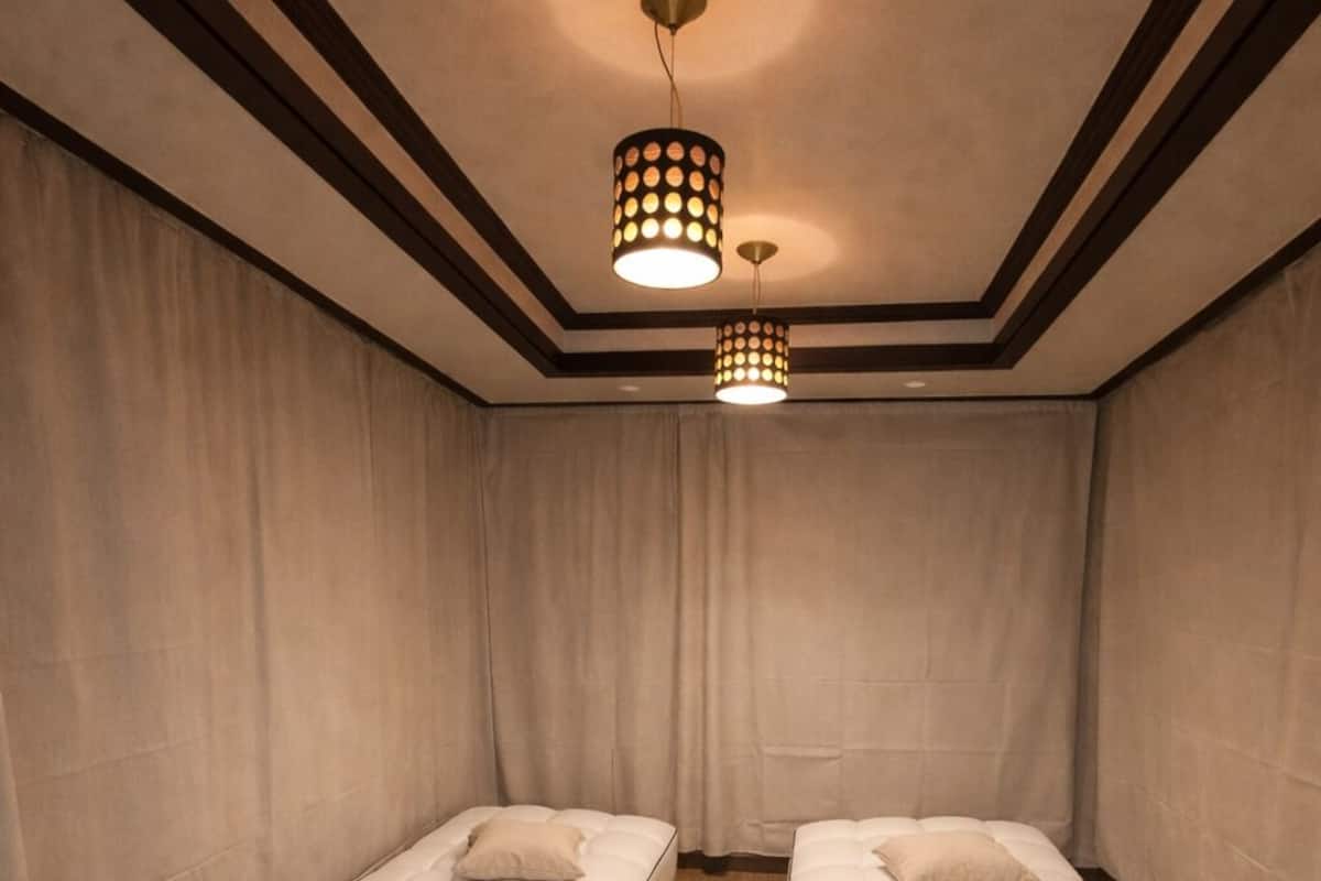 A room with two beds, wooden flooring, and a ceiling light fixture.