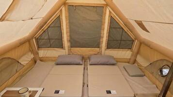 A tent with two beds, a table with a mug, and a portable heater.