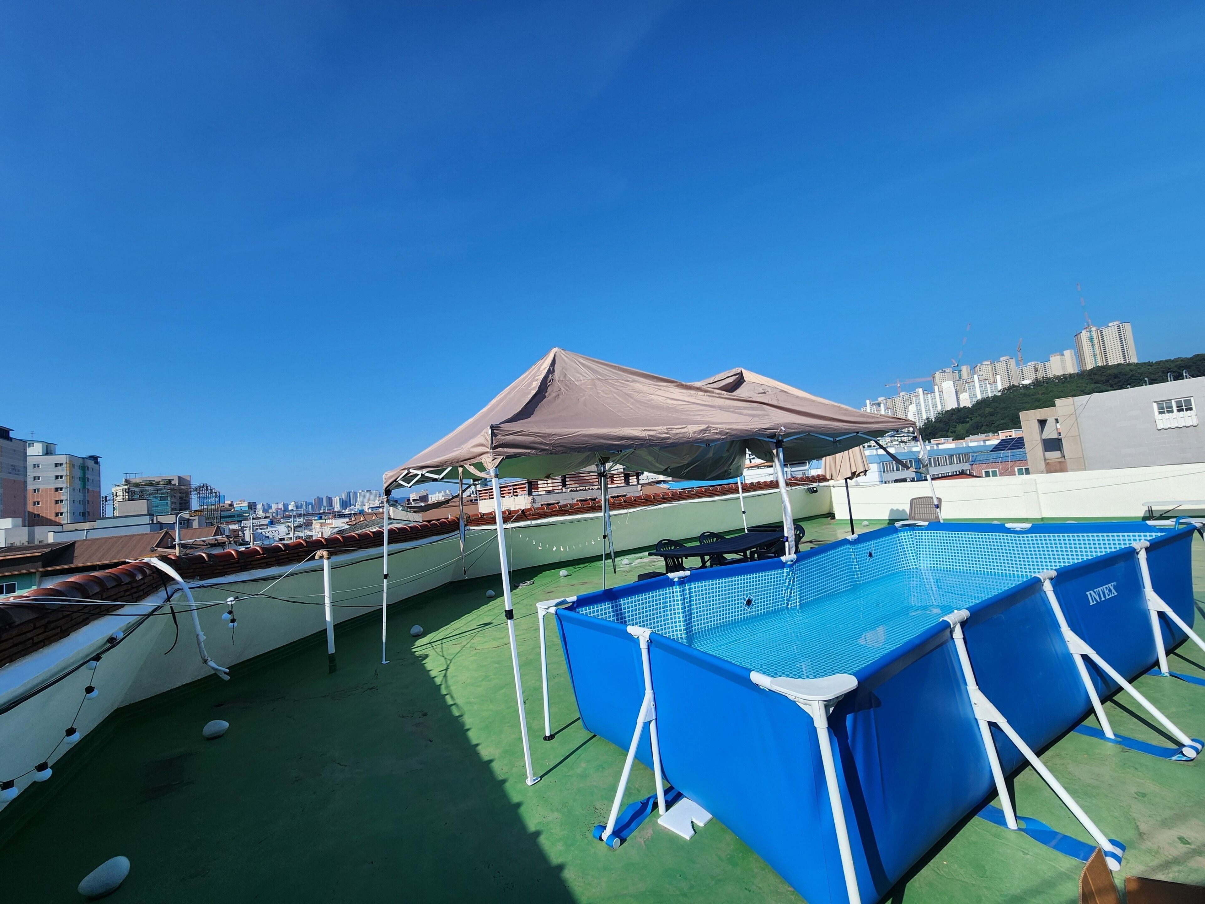 A rooftop pool area with a blue pool, a covered seating area, and boats.