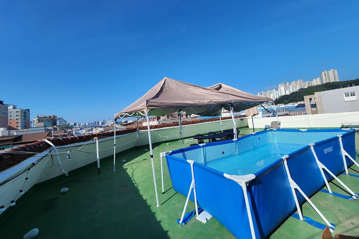 A rooftop pool area with a blue pool, a covered seating area, and boats.