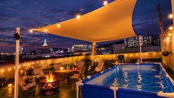 A rooftop pool area with a view of the city skyline at dusk.