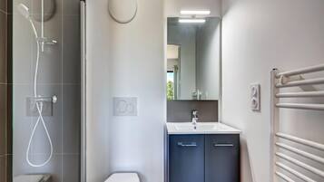 Un baño moderno con ducha, inodoro, lavabo y espejo.