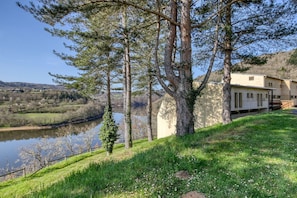 A house by a lake with a grassy area and trees.