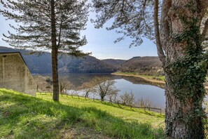 Una vista tranquila de un lago con una estructura de concreto, árboles y un área con césped.