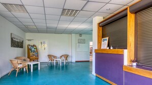 Un espace d’accueil comprenant un comptoir, des chaises, une petite table et un panneau d’affichage.