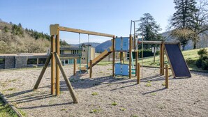 Une aire de jeux avec des balançoires, un toboggan et des structures d’escalade.