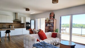 Een moderne woonkamer met een bank, een eethoek en een keuken.