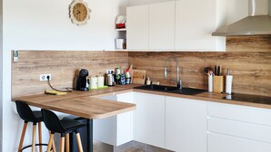 Een moderne keuken met een houten aanrecht, witte kasten, een inbouwspoelbak en een klok aan de muur.