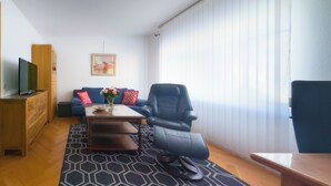 A modern living room with a sofa, a massage chair, a coffee table, and a TV on a wooden cabinet. - Cozy vacation apartment in Winsen an der Luhe for 2-3 persons (Winsen (Luhe))