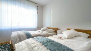 A hotel room with two beds, a window with blinds, and a white wall. - Cozy vacation apartment in Winsen an der Luhe for 2-3 persons (Winsen (Luhe))