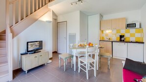 Un espacio habitable pequeño con comedor, kitchenette y una escalera.