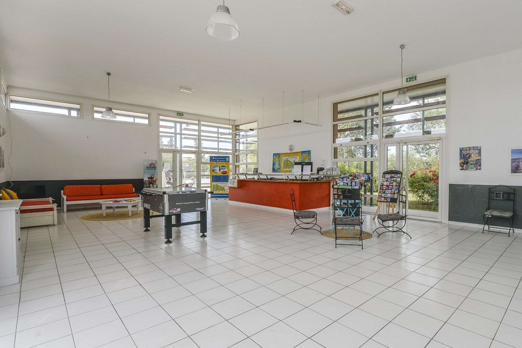 En rummelig lobby med reception, sofa, sofabord og et billardbord.