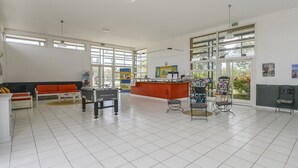 Um hall amplo com balcão de recepção, sofá, mesinha de centro e mesa de bilhar.