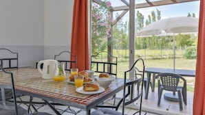 Uma mesa de café da manhã com croissants, suco de laranja e uma cafeteira.