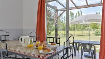 A breakfast table with croissants, orange juice, and a coffee pot.