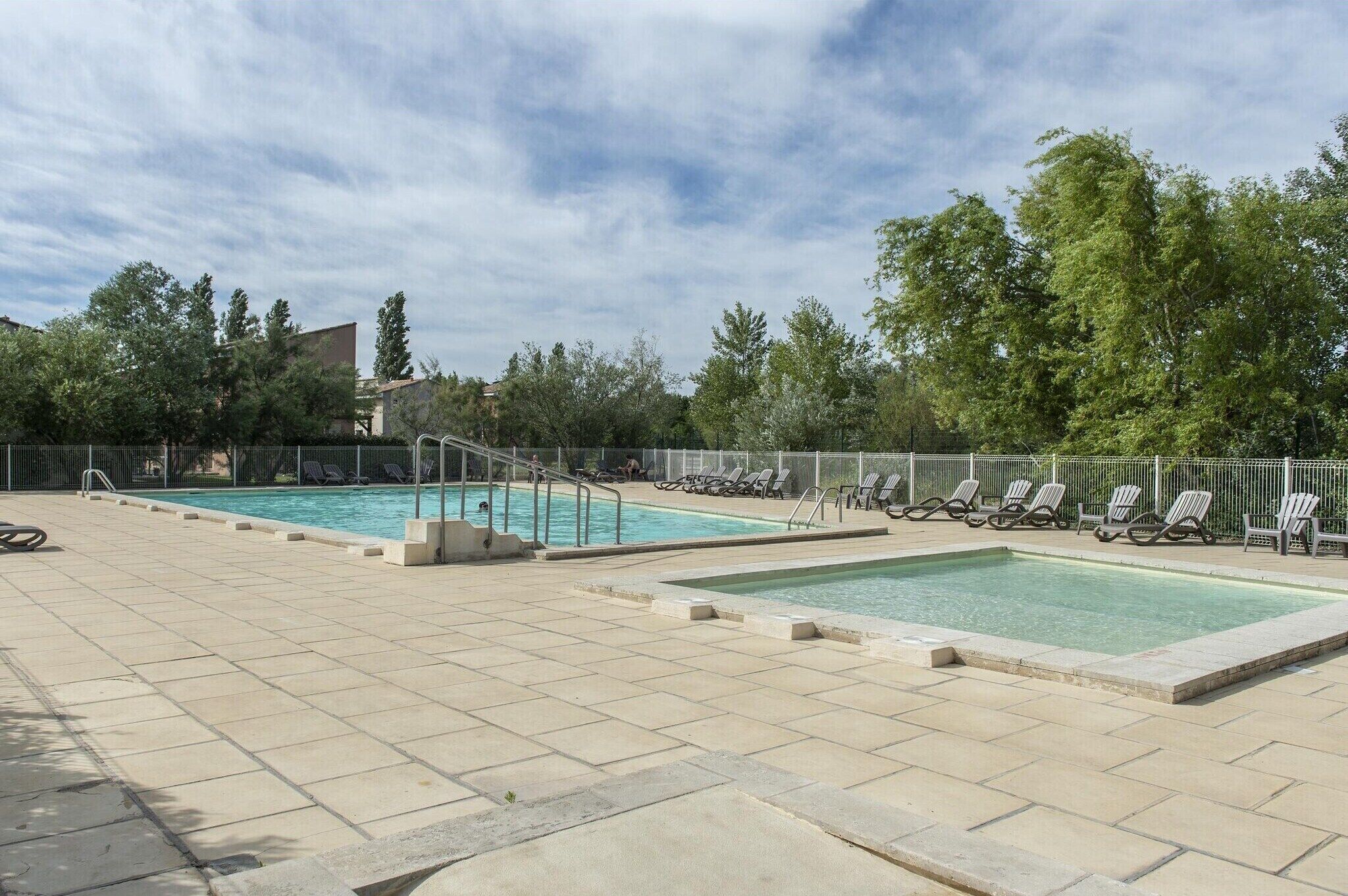 Et poolområde med flere swimmingpools, liggestole og en afspærret terrasse.