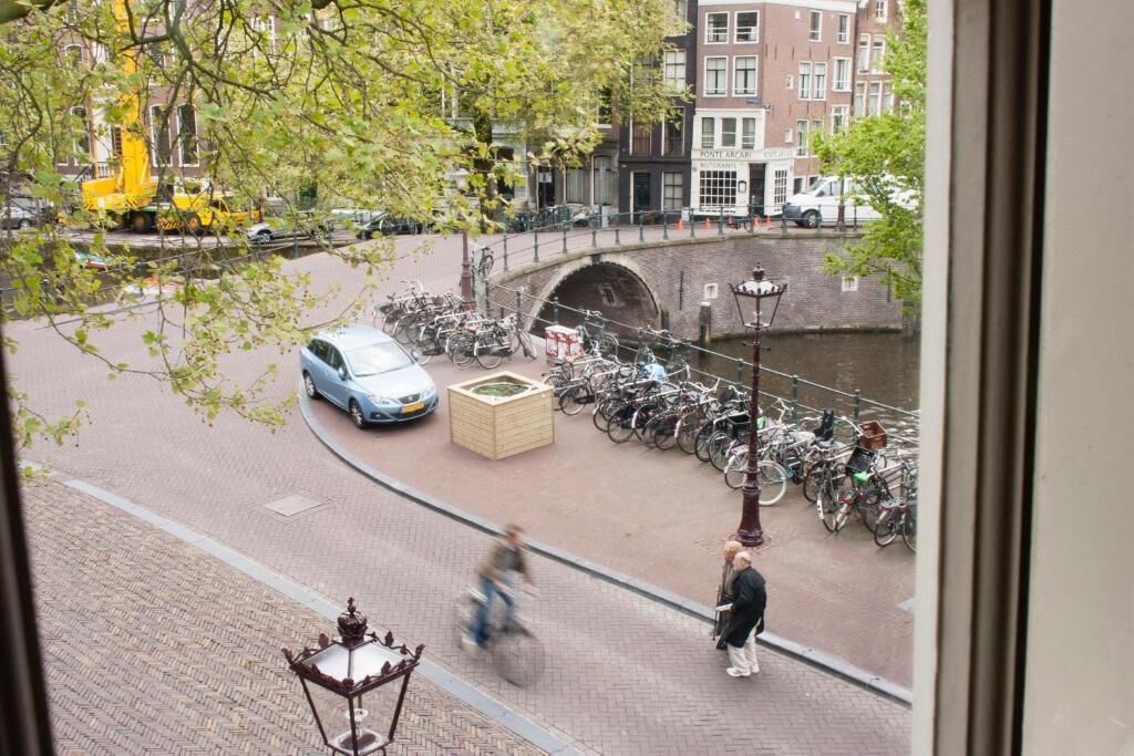 Una calle al lado de un canal, con bicicletas, un puente y edificios.