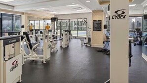Uma academia com equipamentos Cybex, janelas amplas e vista para a cidade.