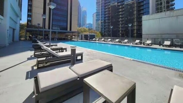 Piscina no terraço com espreguiçadeiras e vista para edifícios altos.