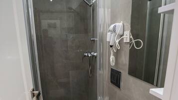Een moderne badkamer met een glazen douchecabine, een wit toilet en een wastafel met spiegel.