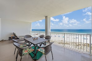 A covered outdoor seating area with wicker furniture and a view of the beach. - Summer House 503B (Orange Beach)