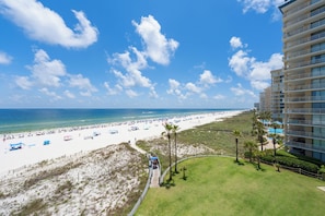 A beach resort with a pool, beach umbrellas, and a high-rise building. - Summer House 503B (Orange Beach)