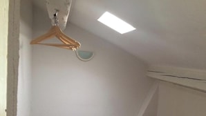 Et rum med skrå vægge, en træbøjle og en lille vægmonteret lampe.