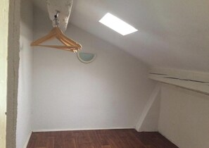 A room with a sloped ceiling, a wooden hanger, and a small wall-mounted light fixture. - Loft des arenes (Béziers)
