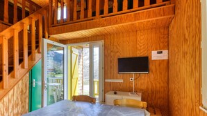 A wooden interior with a bed, a TV, and a staircase.