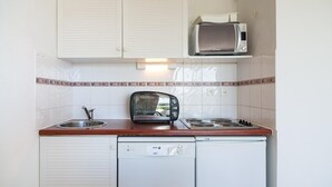 Uma cozinha compacta equipada com micro-ondas, torradeira, pia e máquina de lavar louça.