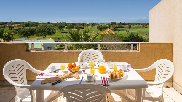 Varanda com mesa posta para o café da manhã, com vista para um campo de golfe.