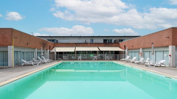 En swimmingpool med liggestole og en overdækket terrasse.