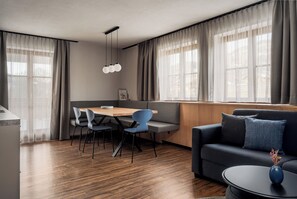 Ein modernes Wohnzimmer mit einer Couch, einem Esstisch mit Stühlen und einer Küchenzeile.
