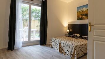 A bedroom with a bed, a painting on the wall, and a sliding glass door to the outside.