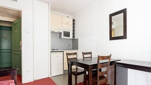 Une cuisine compacte avec des meubles blancs, un four à micro-ondes et un coin repas comprenant une table et des chaises.