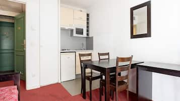 A compact kitchen with white cabinets, a microwave, and a dining area with a table and chairs.