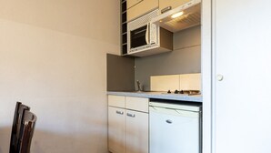 Een kleine keuken met een magnetron, vaatwasser en een klein aanrecht.