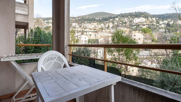 Een balkon met een tafel en stoel, met uitzicht op een stad met gebouwen en heuvels.