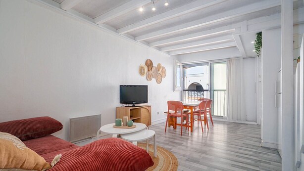 Een moderne woonkamer met een bank, televisie en eethoek.