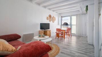 Ein modernes Wohnzimmer mit Sofa, Fernseher und Essbereich.