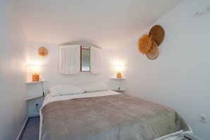 A bedroom with a bed, bedside lamps, a mirror, and a wall decoration. - Apartment with Mezzanine in Cap d'Agde (Agde)