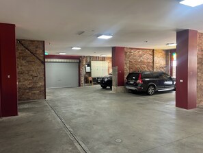 A parking garage with a brick wall, a closed garage door, and a parked SUV.