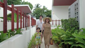 Una familia caminando por un sendero con un edificio blanco y barandillas rojas.