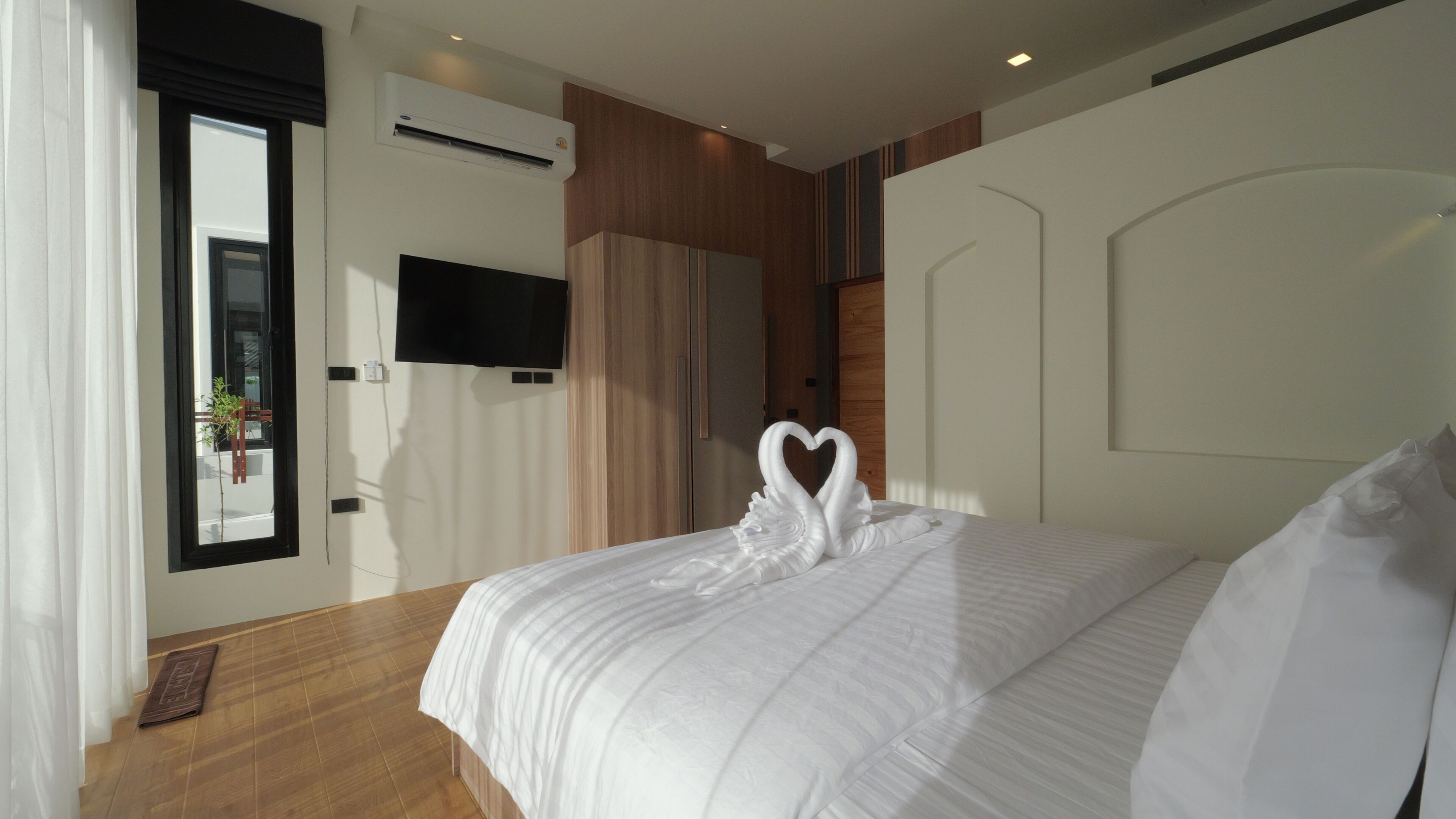Habitación de hotel con cama, televisión de pantalla plana, aire acondicionado y ventana con cortinas.