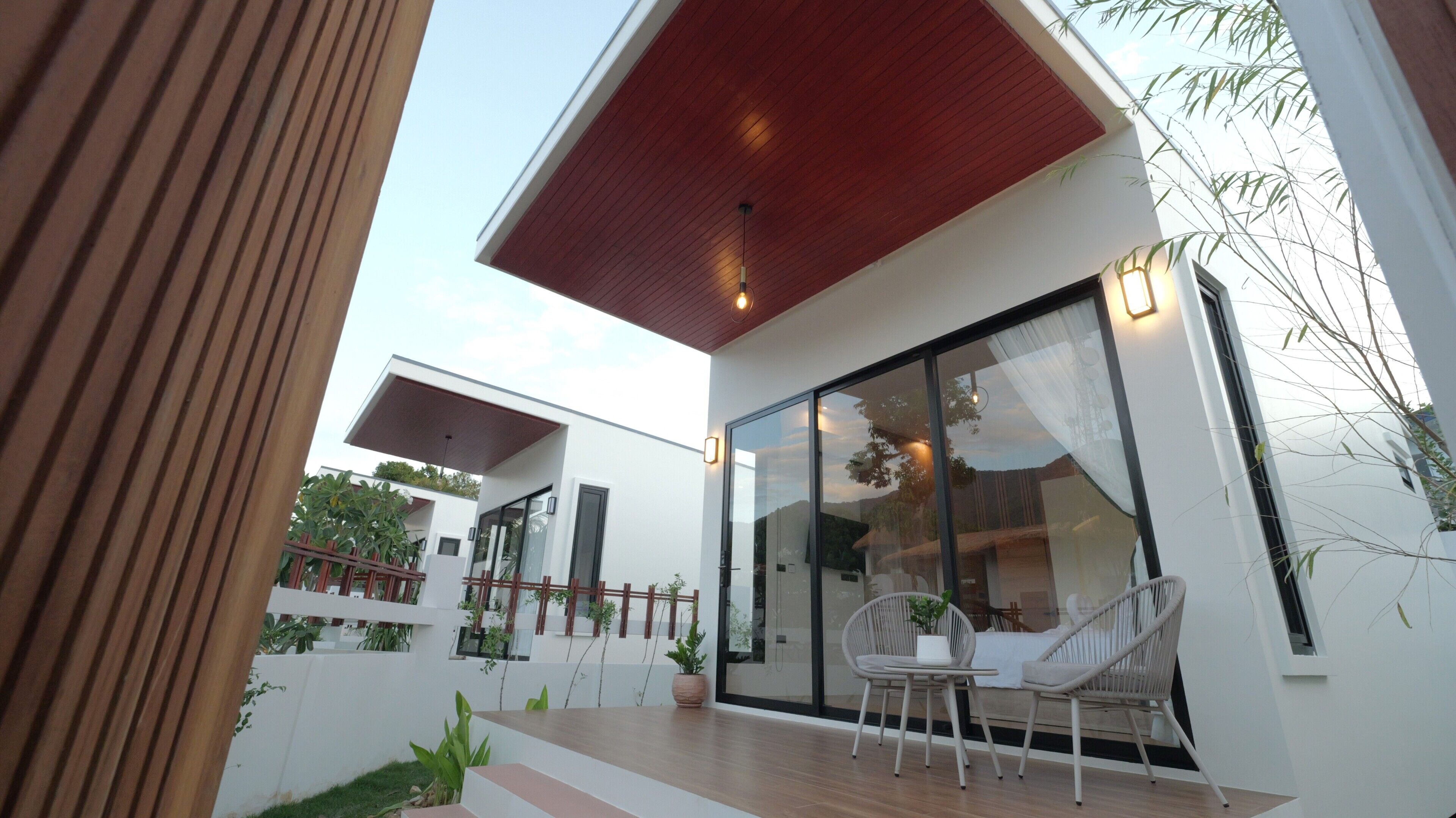 A modern house with a large glass door, a wooden deck, and outdoor seating.