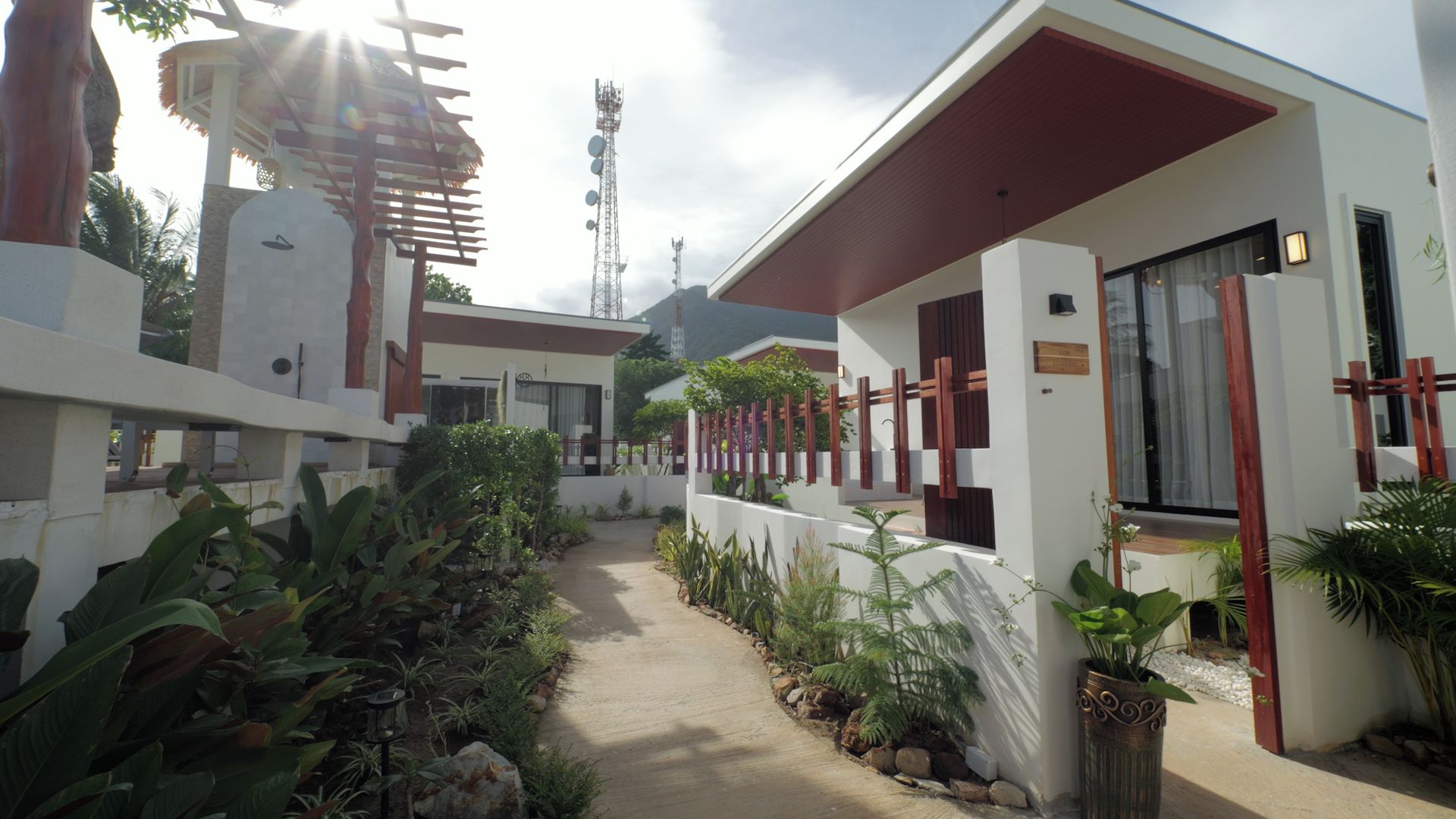 A modern building with a covered walkway, surrounded by tropical plants and a clear sky.