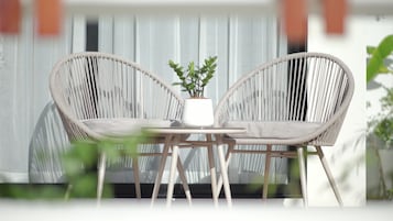Un conjunto de silla y mesa de mimbre al aire libre, con una planta en maceta en el centro.